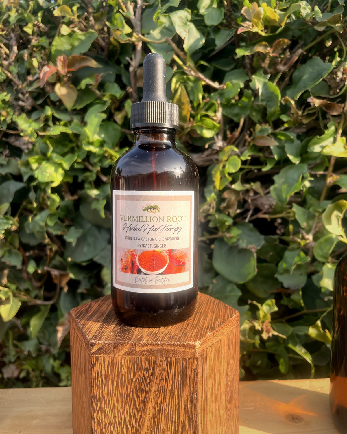 Amber dropper bottle labeled Vermilion Root Herbal Heat Therapy on a wooden stand